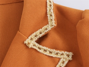 Detailed macro view of orange woven texture fabric with gold and white fringe edge decoration