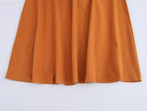 Detail shot of ginger orange faux suede dress hem with smooth stitching and drape