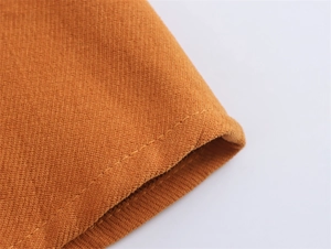 Detailed macro view of the ginger yellow corduroy fabric texture and precision stitching