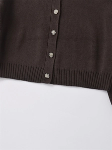 Dettaglio del cardigan in maglia marrone scuro con bottoni testurizzati e bordo a coste