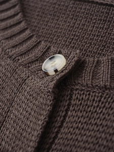 Dettaglio del cardigan in maglia marrone con trama a coste e bottone effetto tartaruga