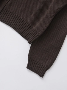 Dettaglio macro del cardigan in maglia marrone scuro con polsini e orlo a coste