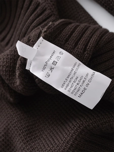 Dettaglio macro del tessuto a maglia marrone scuro con etichetta 100% poliestere