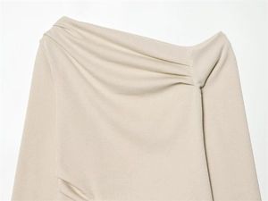 Detail of beige asymmetric knitted top showing textured fabric and draped pleated neckline