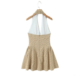 Detail of beige halter dress featuring black polka dots and pleated neckline textures