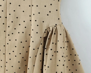 Detailed view of khaki polka dot dress showing gathered fabric and textured cotton blend