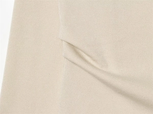 Close-up of premium beige piqué knit fabric showing soft texture and fine grain detail