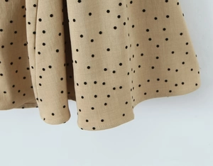 Detail of khaki fabric with black polka dots and pleated drape of the dress
