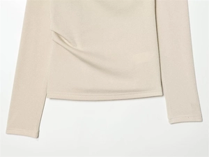 Detailed close-up of beige piqué fabric and slim-fit stitching on asymmetrical top
