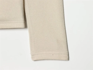 Close-up of beige piqué fabric texture and high-quality stitching on asymmetric top
