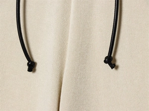 Detailed macro view of off-white waffle knit fabric with black leather knotted drawstrings