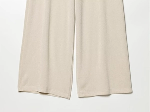 Detailed macro view of the knitted piqué fabric texture on light beige wide-leg pants