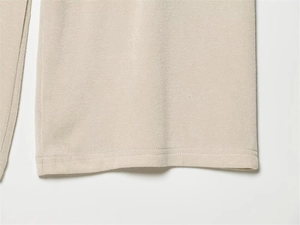 Detailed close-up showing the precise double-needle hem stitching on beige knitted fabric