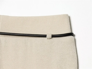 Close-up of knit fabric texture with black leather belt on beige trousers