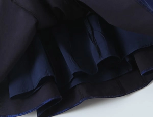 Gros plan d'un ourlet de robe bleu foncé avec design double couche et détails fins