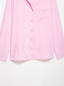 Detailed macro shot of the light pink shirt texture with color-matched buttons and pocket