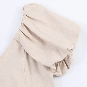 Detailed close-up of beige puff sleeve with delicate pleats and natural linen texture