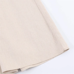 Macro detail of natural cotton-linen fabric texture and double-stitched hem on the dress