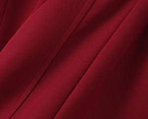 Détail de tissu rouge foncé montrant des coutures de qualité et une texture plissée