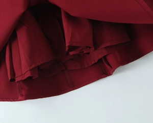Détail de l'ourlet plissé rouge foncé avec tissu lisse et coutures soignées