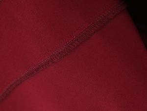 Détail macro du tissu rouge vin montrant la couture surjetée et la texture du tricot