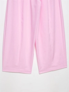 Detail of light pink wide-leg trousers showing crisp center crease and woven fabric texture