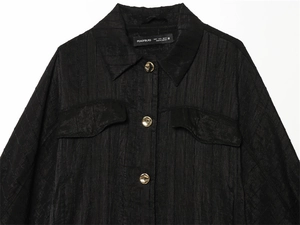 Detail of black safari shirt with jacquard texture and gold embossed buttons