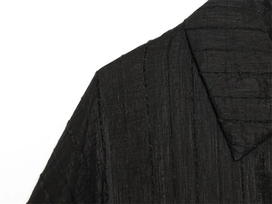 Detailed macro view of the black safari shirt fabric with vertical ribbed texture