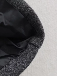 Detailaufnahme von dunkelgrauem Wollstoff mit glattem schwarzem Futter und Naht am Mantel