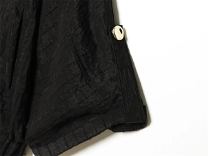 Detailed macro view of black pleated fabric with a polished gold button accent
