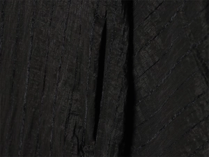 Macro view of black safari shirt fabric showing vertical pleats and pocket detail