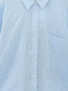 Dettaglio di una camicia in lino azzurro con colletto classico e bottoni bianchi