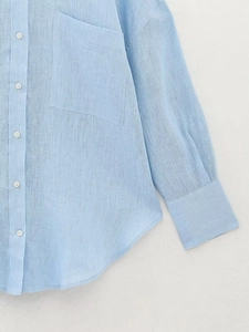 Dettaglio camicia in lino azzurro con taschino sul petto e bottoni bianchi classici