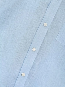 Dettaglio della trama della camicia in lino azzurro con bottoni bianchi e cuciture tasca
