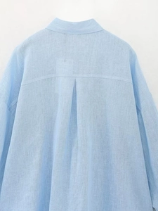 Dettaglio del retro di una camicia di lino azzurra con piega e trama naturale