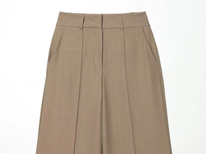 Detail of high-waist brown trousers showing durable twill texture and center crease