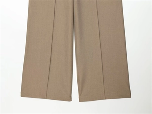 Detail showing the clean hem stitching and central crease on khaki wide-leg trousers