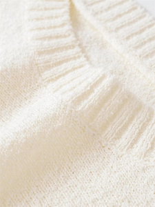 Detail of the ribbed V-neckline and soft boucle knit texture on this white sweater