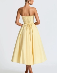 Detail van de vetersluiting aan de achterkant van een gele strapless jurk met textuur