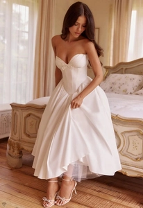 Detail van de korsettafwerking en strik op een witte strapless midi-jurk in Franse stijl