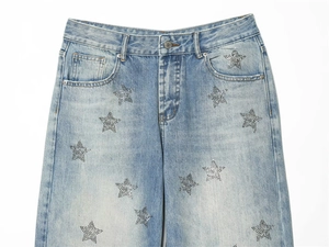 Close-up of sparkling rhinestone star patterns on light blue stonewashed denim jeans