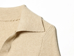 Dettaglio ravvicinato del colletto polo in maglia beige con trama di tessuto a costine
