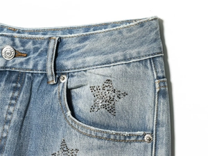 Detail of light blue denim waist with silver button and sparkling rhinestone stars