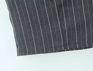 Close-up of charcoal grey pinstripe vest fabric with white vertical stripes and stitching