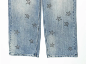 Detail of light blue denim fabric with sparkling star rhinestones on the pant leg