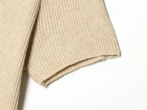 Vista macro dettagliata della trama in maglia a coste beige e del tessuto morbido del polso