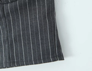 Macro detail of charcoal grey pinstripe suit fabric showing texture and stitching
