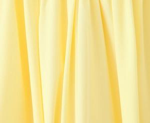 Detailopname van de verticale kreukeltextuur van de lichtgele chiffonstof van dichtbij
