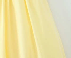 Detailopname van lichtgele strikstof met elegante plooien en een zachte draperende textuur