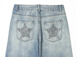Detail view of denim pockets with sparkling rhinestone star patterns on light blue jeans